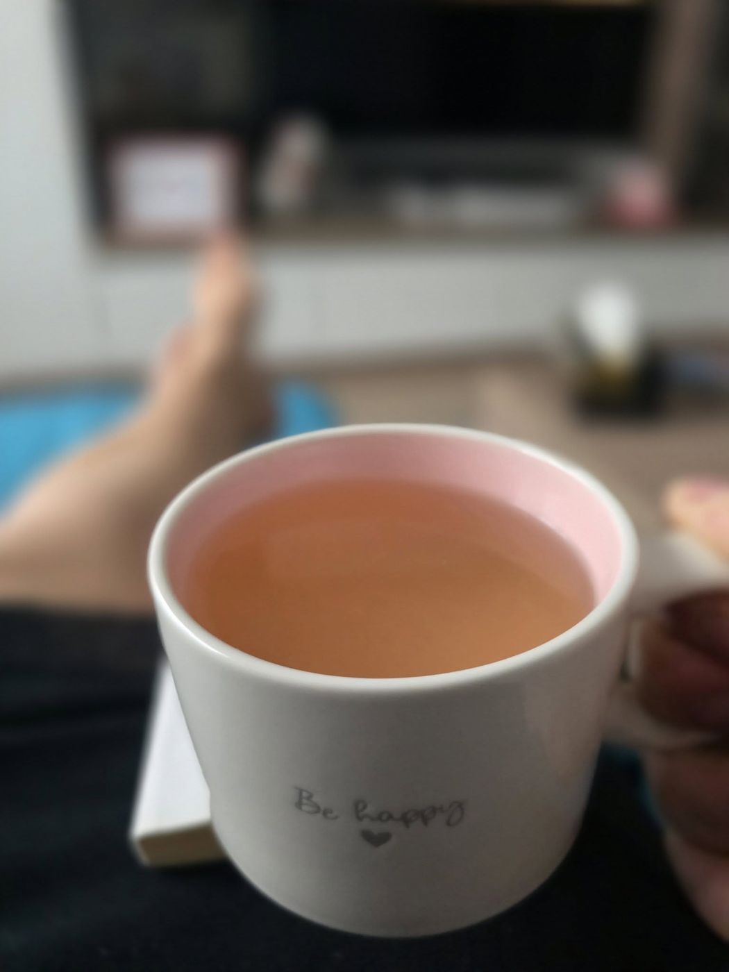 Cana de ceai cu mesajul Be happy, pe masa din cabinet